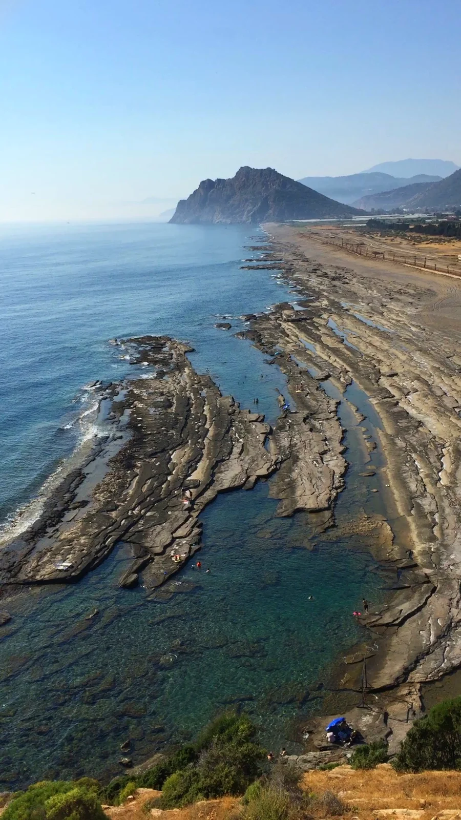 Natural rock pools and layered limestone shore at Koru Beach in Gazipaşa