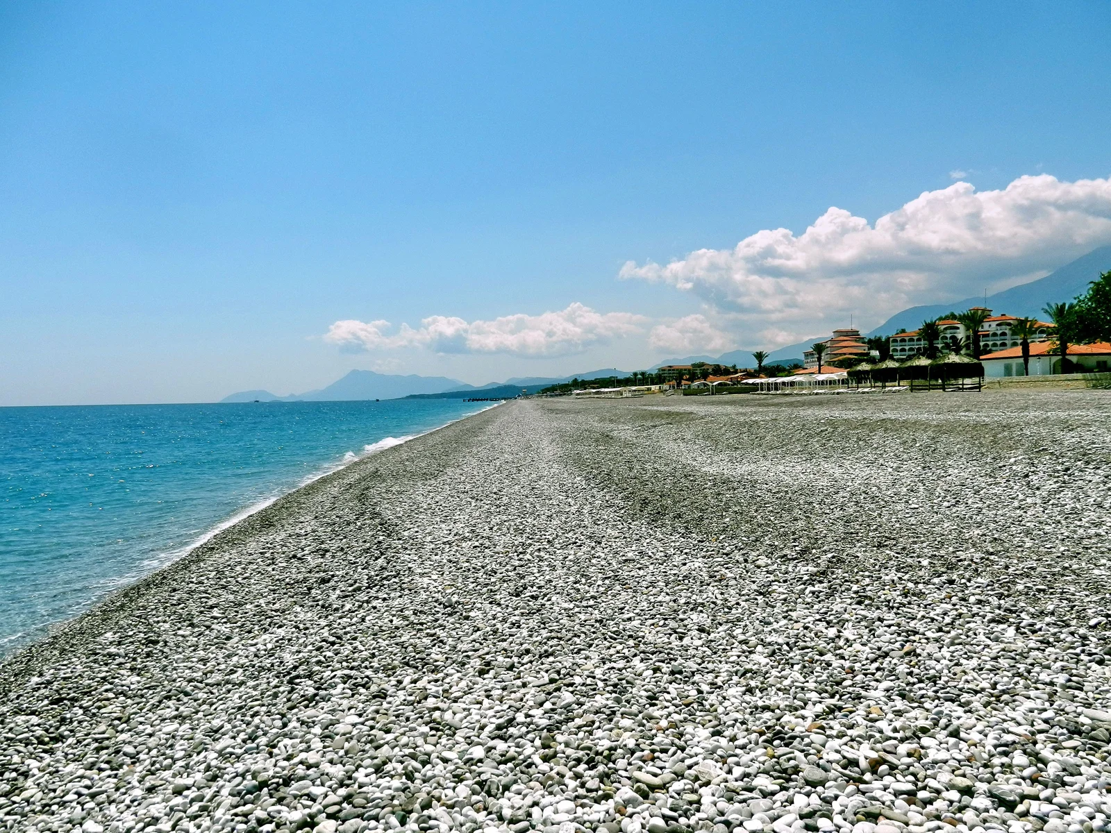 Pebble shoreline of Kiriş Beach with the Mediterranean and coastal hotels